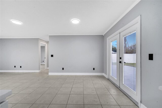 empty room featuring light tile patterned floors, ornamental molding, and french doors