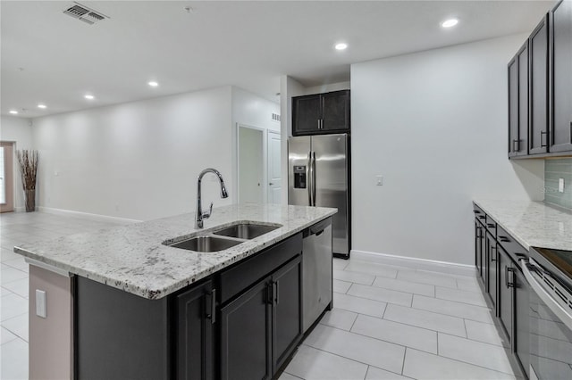 kitchen with light tile patterned floors, appliances with stainless steel finishes, a center island with sink, and sink