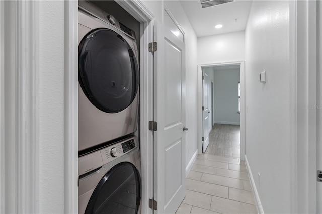 laundry room with stacked washing maching and dryer and light tile patterned floors