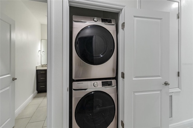 laundry room featuring stacked washer and dryer and light tile patterned floors