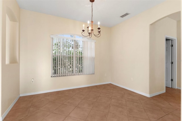 spare room featuring a notable chandelier and light tile patterned flooring