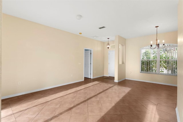 tiled empty room featuring a notable chandelier