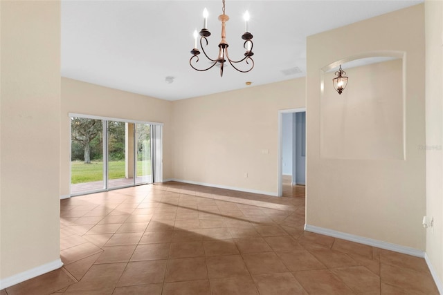 tiled spare room with a chandelier