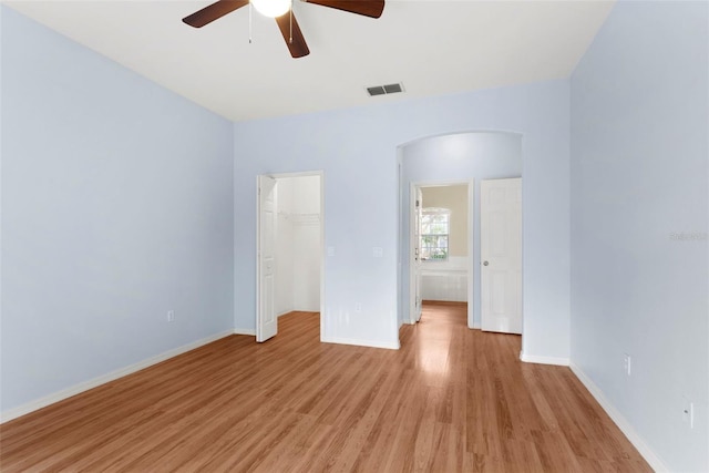 unfurnished bedroom with a spacious closet, ceiling fan, a closet, and light hardwood / wood-style floors