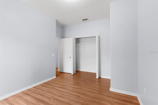 unfurnished bedroom with light hardwood / wood-style floors, a closet, and a textured ceiling