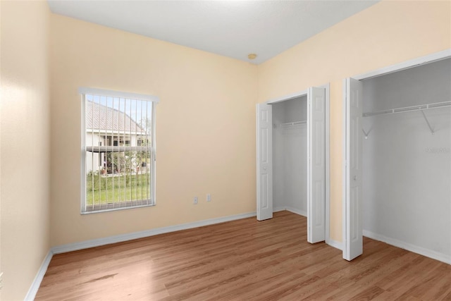 unfurnished bedroom with two closets and light wood-type flooring