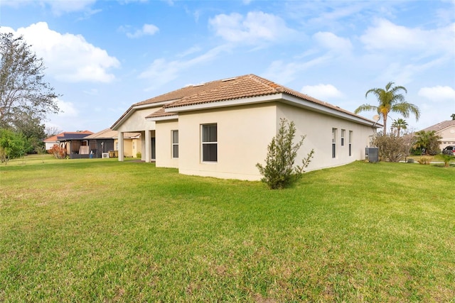 back of property with central air condition unit and a yard