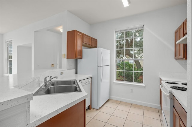 kitchen featuring light stone counters, white appliances, light tile patterned flooring, and sink