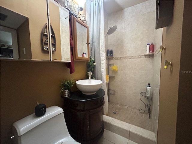 bathroom featuring tile patterned floors, toilet, vanity, and a tile shower