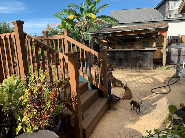 wooden deck with a bar, area for grilling, and a patio