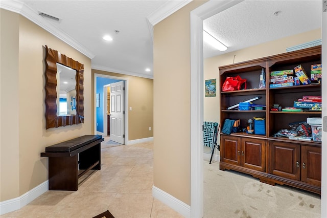 hall with a textured ceiling, light tile patterned floors, and ornamental molding