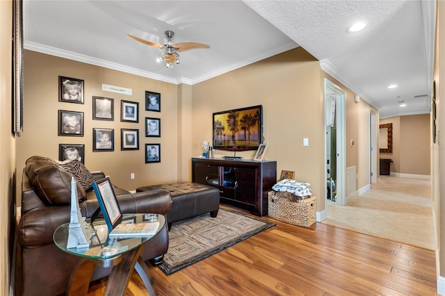 living room with ceiling fan, a textured ceiling, light hardwood / wood-style flooring, and ornamental molding