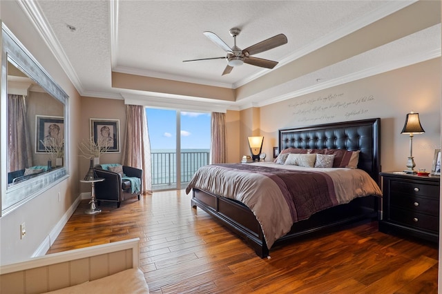 bedroom with ceiling fan, dark hardwood / wood-style floors, a tray ceiling, access to outside, and a textured ceiling