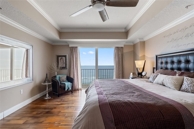 bedroom featuring ceiling fan, access to exterior, a water view, and a tray ceiling