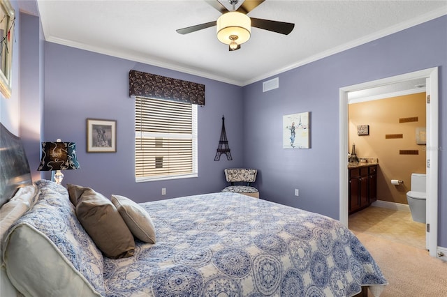 bedroom with ceiling fan, light carpet, ornamental molding, and ensuite bath