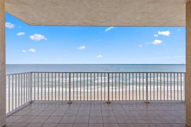 balcony with a water view and a view of the beach