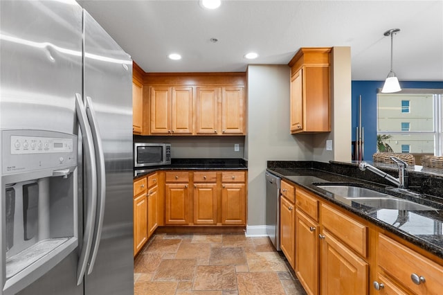 kitchen with sink, pendant lighting, stainless steel appliances, and dark stone counters