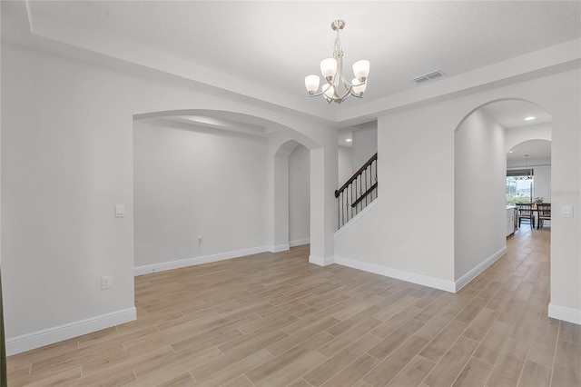 unfurnished room with an inviting chandelier and light hardwood / wood-style flooring