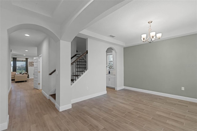 empty room featuring an inviting chandelier and light hardwood / wood-style flooring