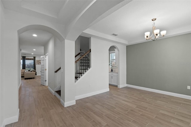 entrance foyer with a chandelier, light wood-type flooring, and a tray ceiling