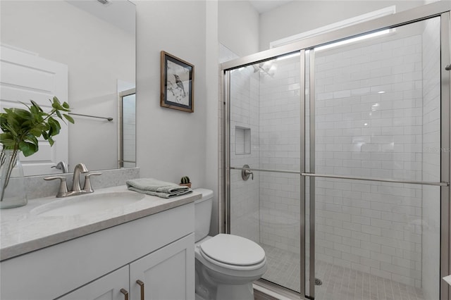 bathroom featuring vanity, toilet, and a shower with shower door