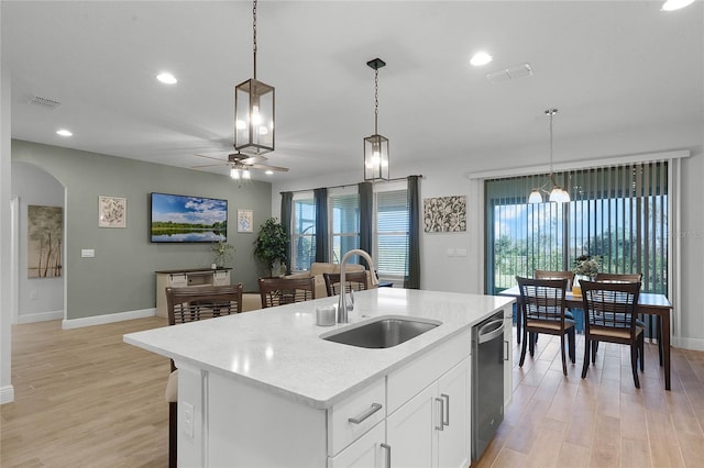 kitchen featuring sink, white cabinetry, an island with sink, decorative light fixtures, and stainless steel dishwasher