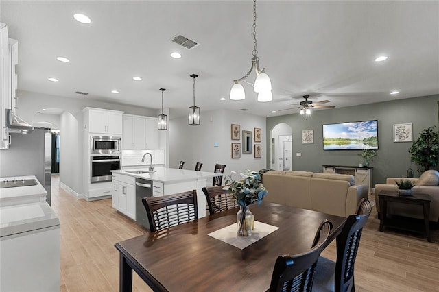 dining space with ceiling fan, light hardwood / wood-style floors, and sink