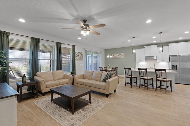 living room featuring a textured ceiling, light hardwood / wood-style floors, and ceiling fan