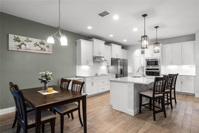 kitchen featuring hanging light fixtures, appliances with stainless steel finishes, sink, and white cabinets