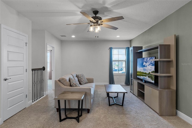 living room featuring light carpet, ceiling fan, and a textured ceiling