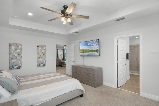 carpeted bedroom with a raised ceiling and ceiling fan