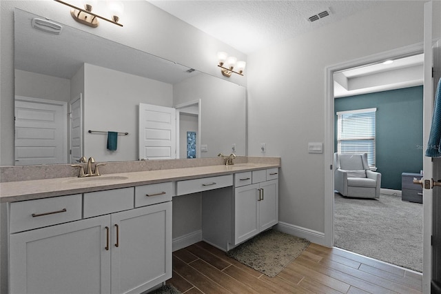 bathroom with wood-type flooring, vanity, and a textured ceiling