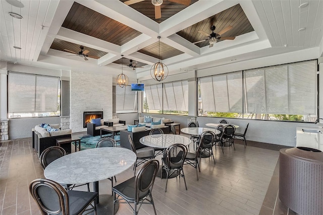 sunroom / solarium with a fireplace, coffered ceiling, ceiling fan, wood ceiling, and beam ceiling