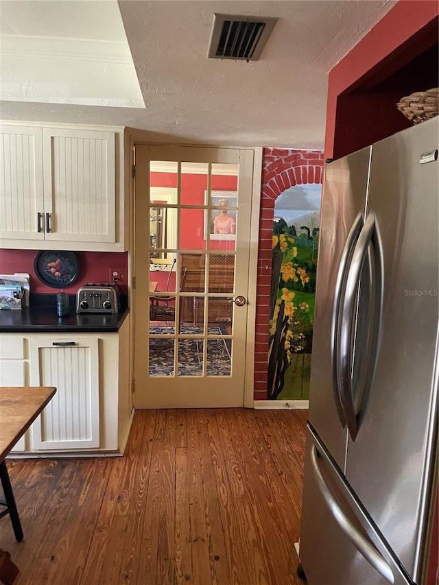 kitchen featuring wood-type flooring, stainless steel fridge, and a textured ceiling