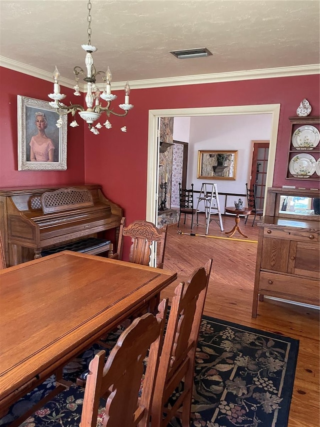 dining room featuring hardwood / wood-style floors, crown molding, a chandelier, and a textured ceiling