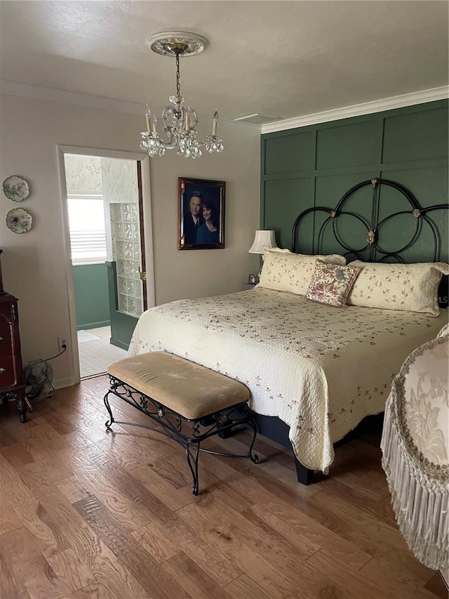 bedroom with an inviting chandelier, ornamental molding, and wood-type flooring