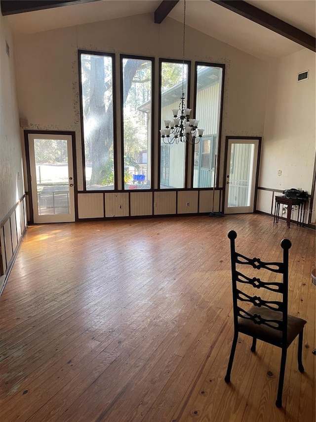 interior space featuring plenty of natural light, vaulted ceiling with beams, and an inviting chandelier