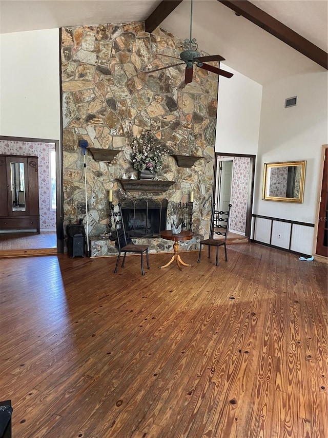 unfurnished living room with ceiling fan, a fireplace, wood-type flooring, high vaulted ceiling, and beamed ceiling