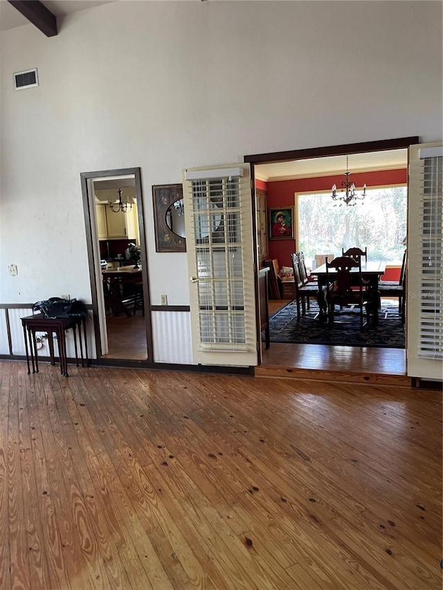 spare room with beam ceiling, a notable chandelier, and hardwood / wood-style floors