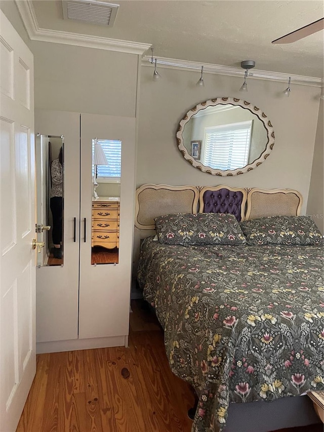 bedroom featuring ceiling fan, wood-type flooring, and ornamental molding