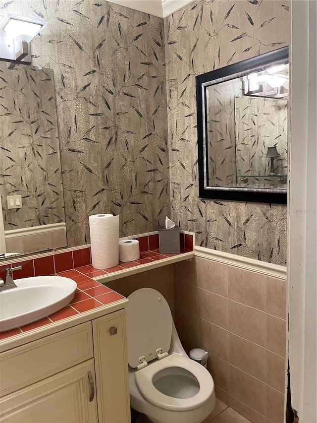 bathroom with toilet, tile walls, and vanity