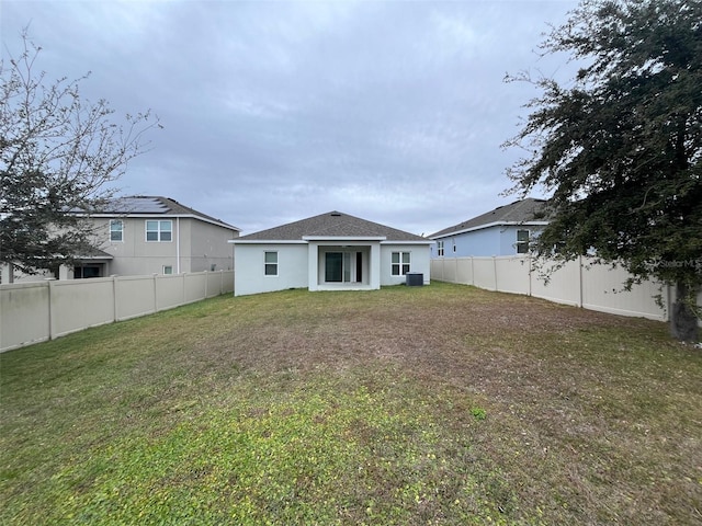 rear view of property featuring cooling unit and a lawn