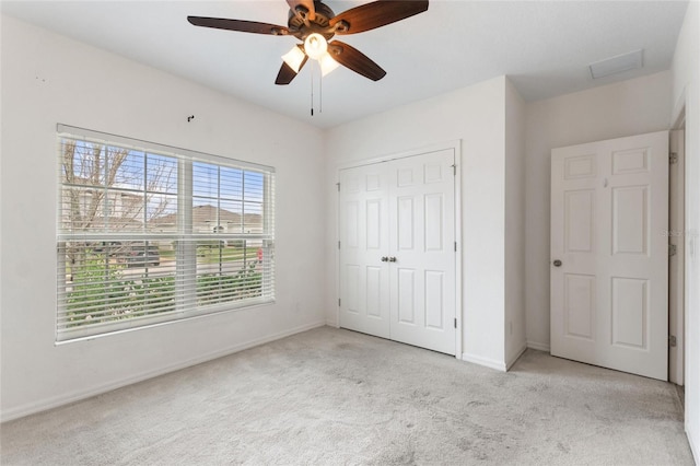 unfurnished bedroom featuring a closet, light colored carpet, and ceiling fan