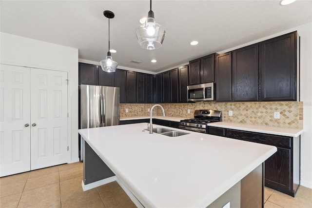 kitchen featuring a center island with sink, sink, light tile patterned floors, appliances with stainless steel finishes, and pendant lighting