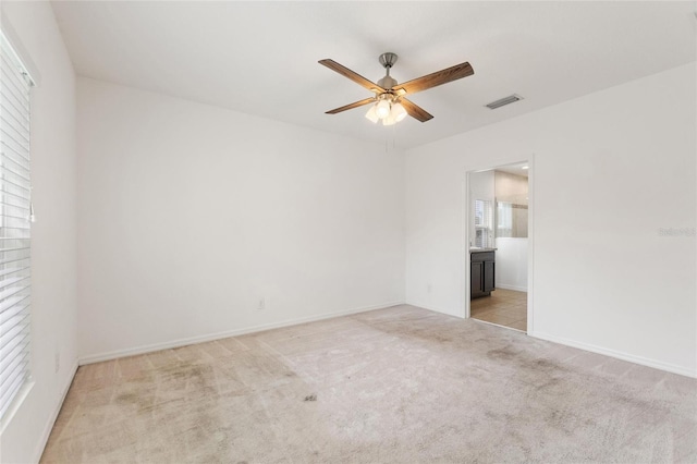 empty room featuring ceiling fan and light colored carpet