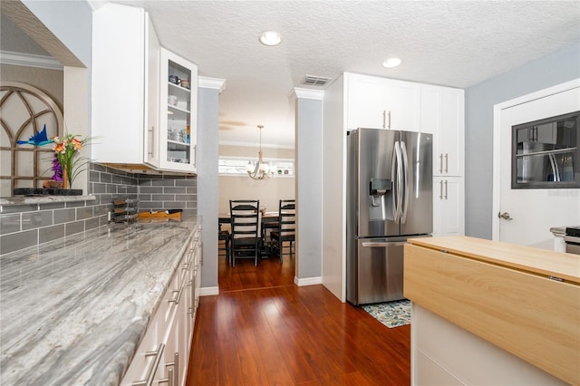 kitchen with stainless steel refrigerator with ice dispenser, light stone countertops, and white cabinets