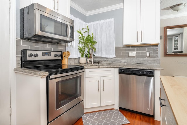 kitchen featuring crown molding, appliances with stainless steel finishes, decorative backsplash, and white cabinets