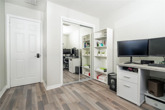 home office with hardwood / wood-style floors and a textured ceiling