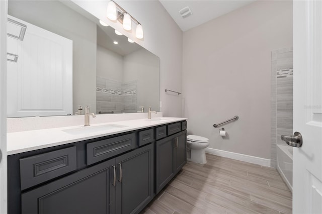 bathroom featuring double vanity, baseboards, toilet, and a sink