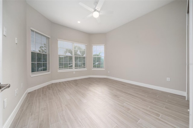 spare room featuring ceiling fan, light wood finished floors, and baseboards